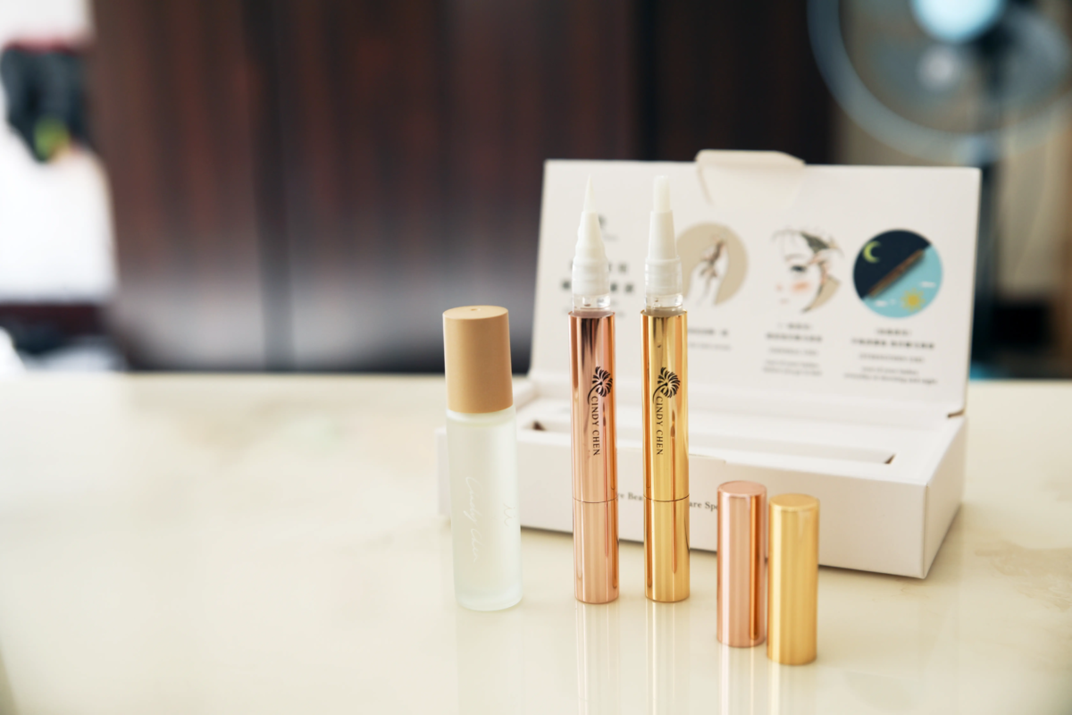 CindyChen金管與粉管的睫毛滋養液、指緣油直立在桌面上